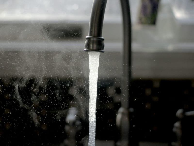 Clear water running from a kitchen faucet into a sink