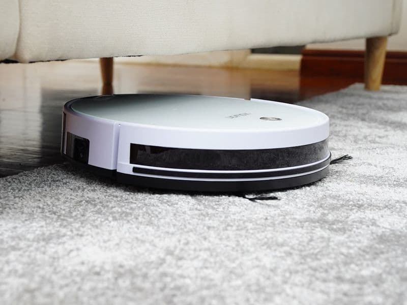 Person using a lightweight cordless stick vacuum on a hardwood living room floor