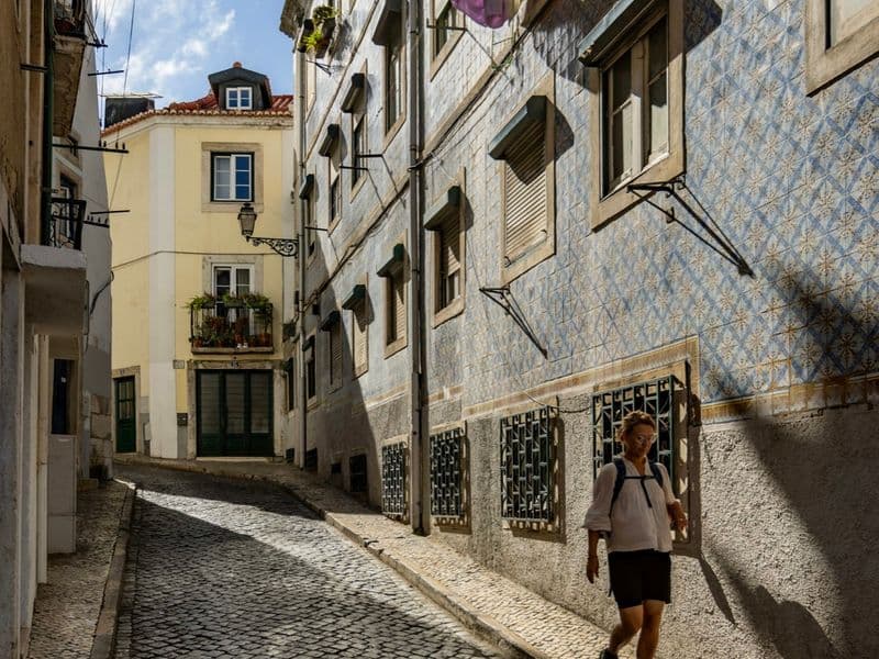 Woman in summer sandals walking down a sunlit cobblestone street