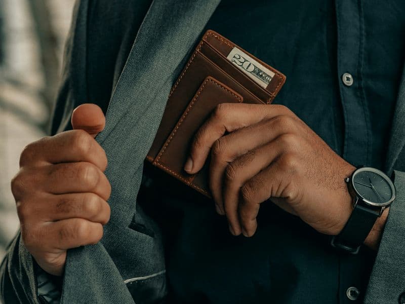 A man holding a slim wallet and watch, everyday-carry lifestyle scene