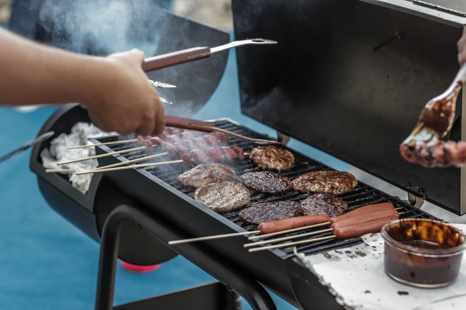 A pellet grill smoking on a backyard patio during a barbecue
