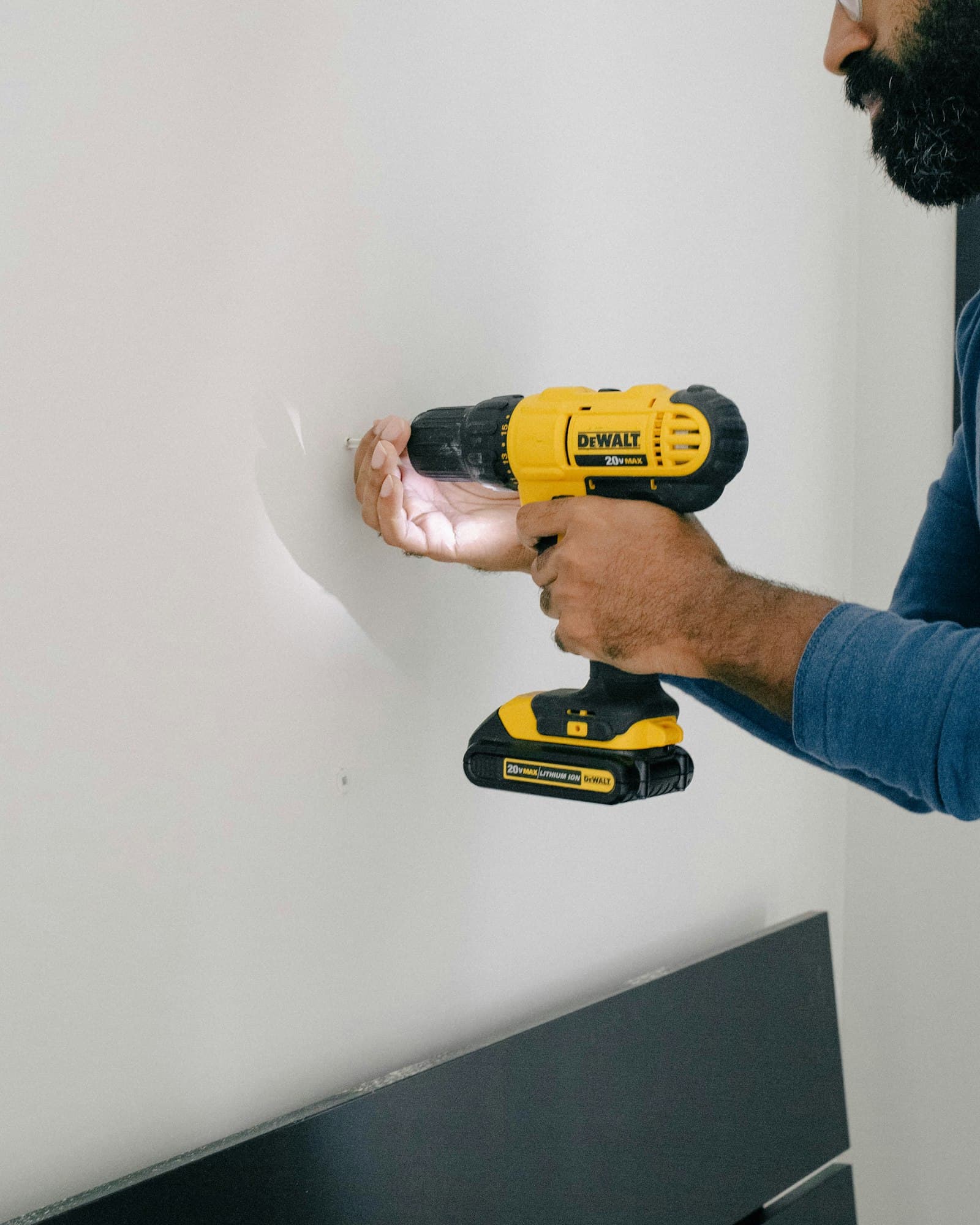 A person driving a screw into a wall with a DEWALT 20V MAX cordless drill/driver