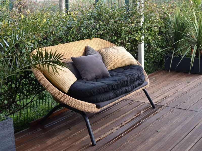 A sunlit backyard patio with cushioned outdoor lounge seating