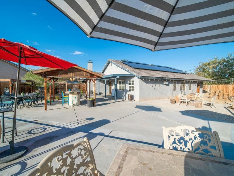 An attractive backyard patio with a dining table, chairs, and umbrellas in a landscaped yard