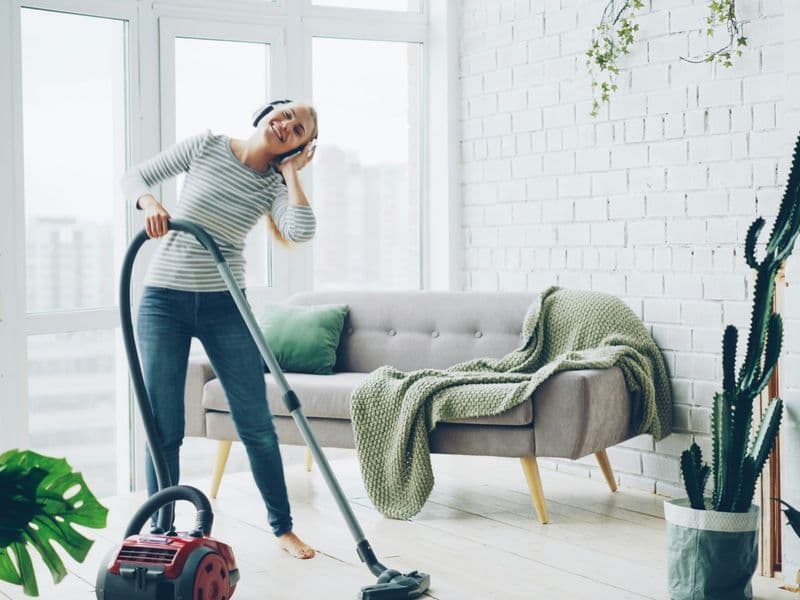 Person vacuuming a bright modern living room with an upright vacuum