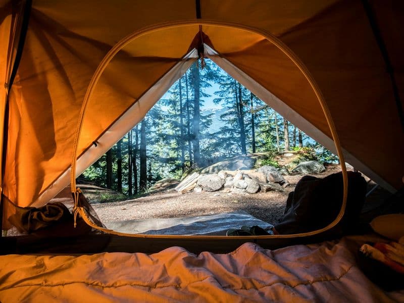 Campsite by a lake at sunrise with gear ready for a weekend trip