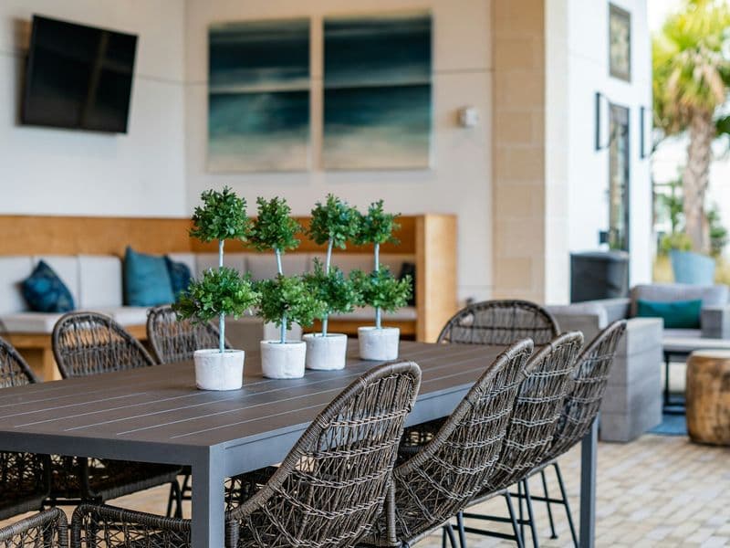 Covered outdoor patio dining area with a long table and woven high-back dining chairs