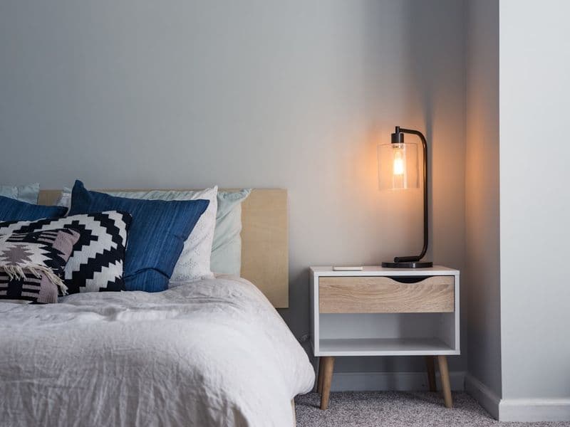 A lightweight cooling comforter on a neatly made bed in a cool, bright bedroom