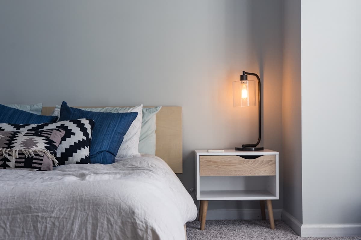 A lightweight cooling comforter on a neatly made bed in a cool, bright bedroom