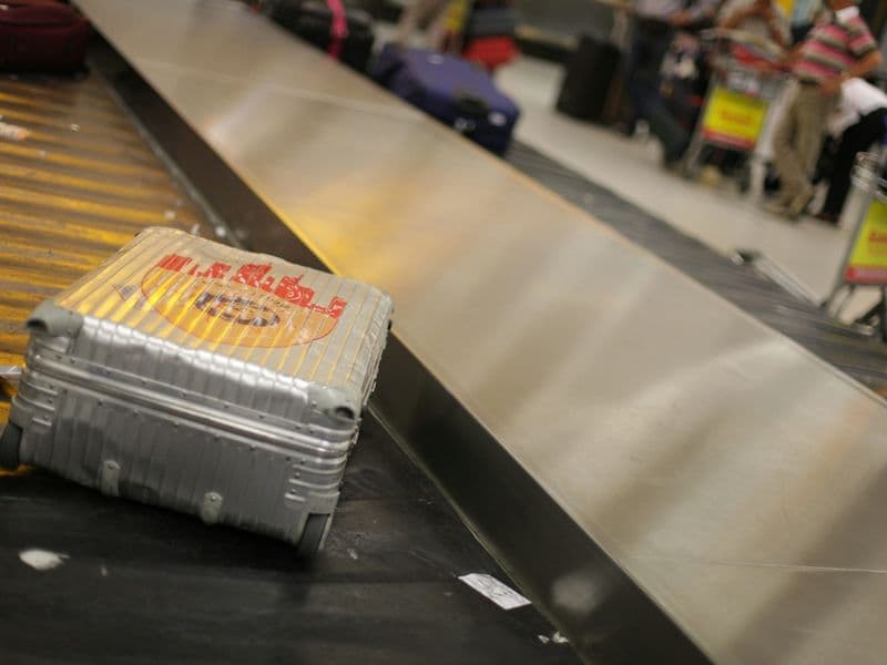 Gray hardside spinner suitcase standing in an airport terminal