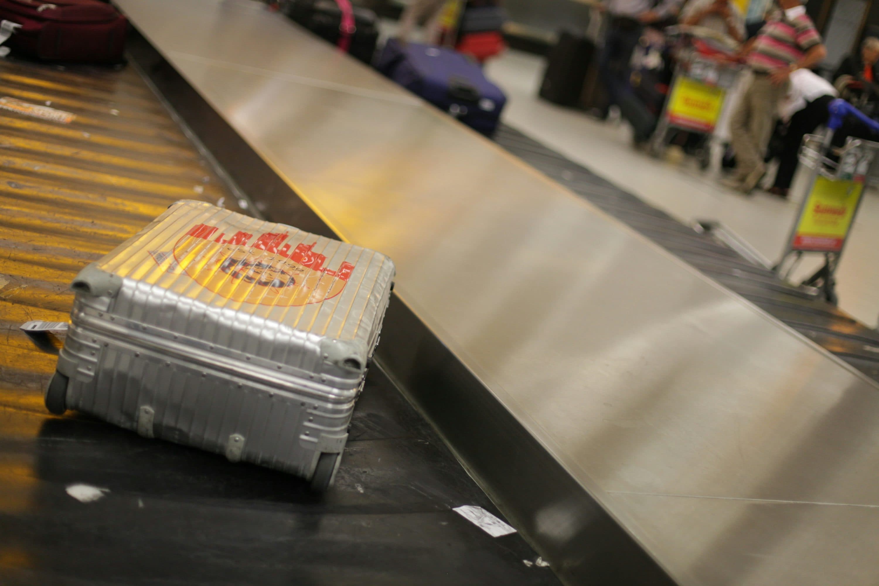 Gray hardside spinner suitcase standing in an airport terminal