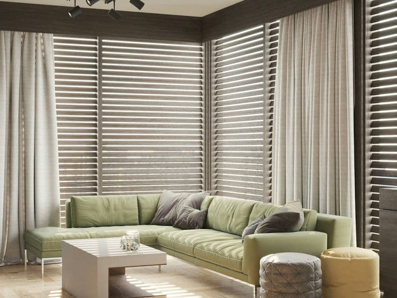 Modern living room with floor-to-ceiling drapery framing the windows, green sofa, and natural light