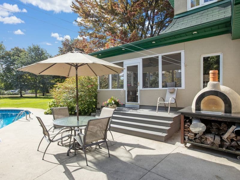 Outdoor patio with table, chairs, and shade beside a swimming pool