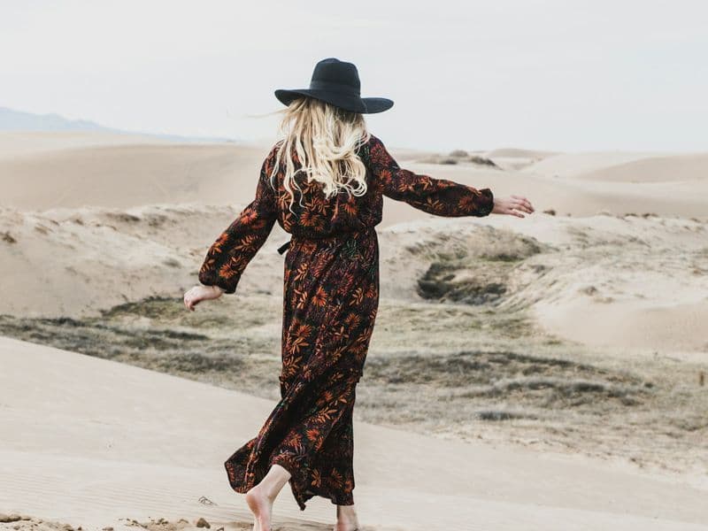Woman in a floral maxi dress walking outdoors in warm summer light