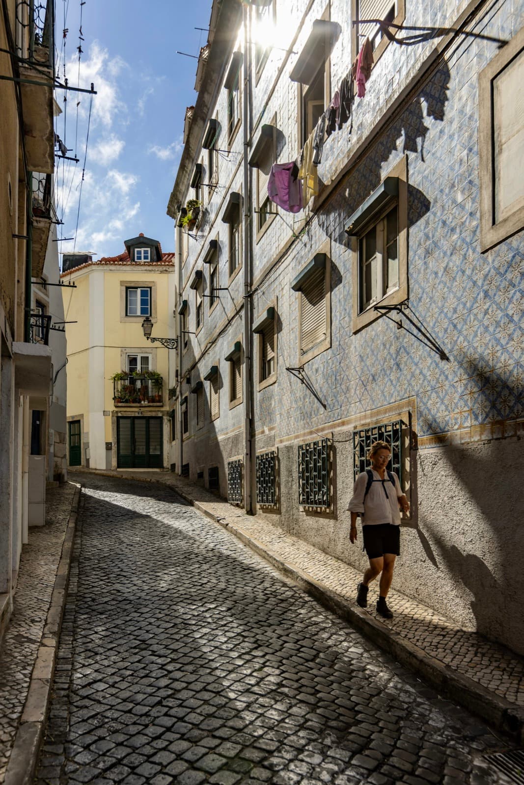 Woman in summer sandals walking down a sunlit cobblestone street